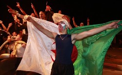 An Algerian fan painted in the country's colors holds the Algeria's flag as he chants The Desert Foxes' heroic qualification into South Africa 2010