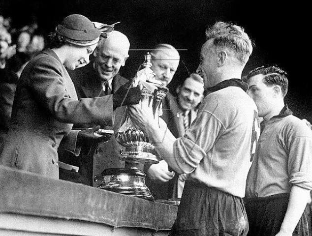 Billy Wright of Wolves receives the FA Cup trophy on behalf of the team after beating Leicester in the finals.